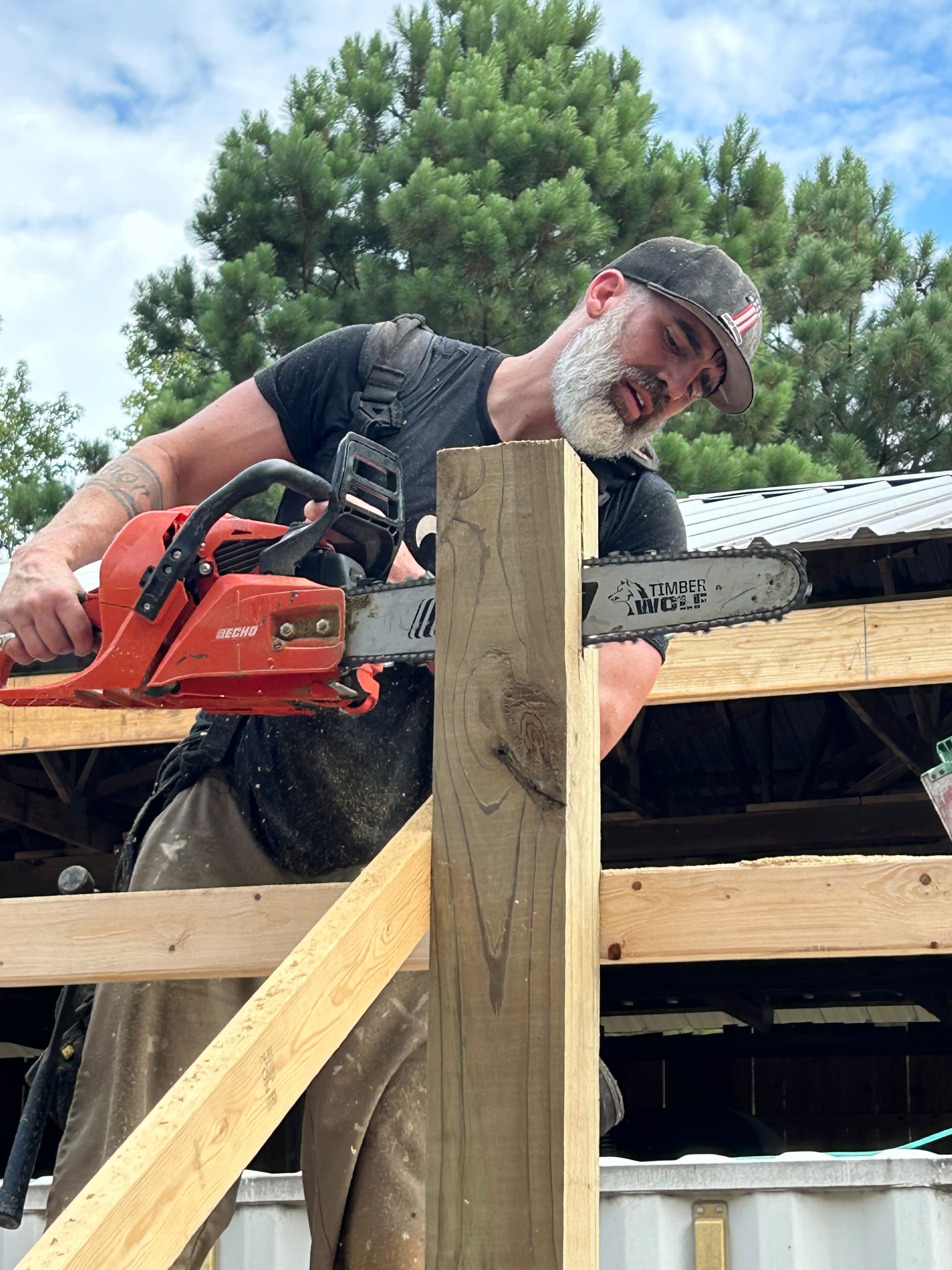 Craftsman cutting timber with chainsaw on framing project